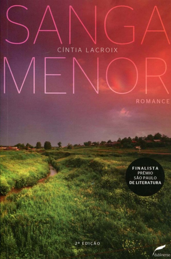 Capa de Sanga Menor, de autoria de Cíntia Lacroix, em que o título e o nome da autora se encontram na metade superior da capa. A imagem é de um campo verde com uma sanga cortando-o, um córrego de águas escuras. O céu está em tons de vermelho e roxo, semelhante ao entardecer.