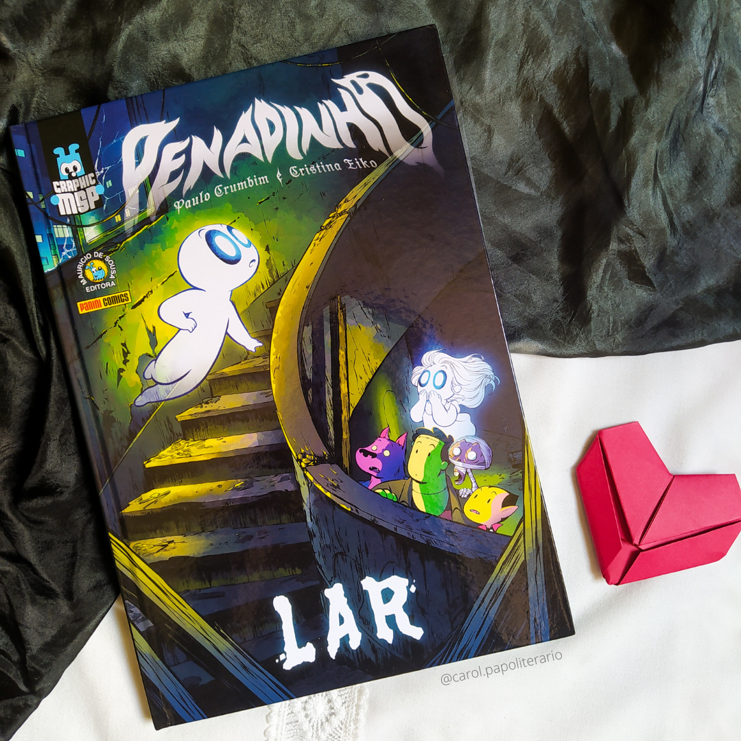 Graphic Novel Penadinho Lar, com um coração de origami ao lado. Na capa, aparece Penadinho como que descendo escadas em curva em um prédio abandonado. Ele está em destaque. Como que escondidos, em um andar abaixo e olhando para Penadinho, estão Lobi, Alminha, Frank, Muminho e Zé Vampir.
